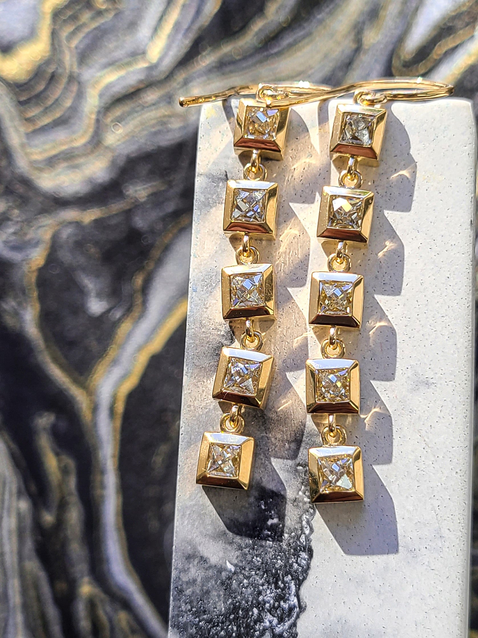 Ten French cut diamonds bezzle set in Single Stone's 'Karina' setting and linked together two create two yellow gold duster earrings