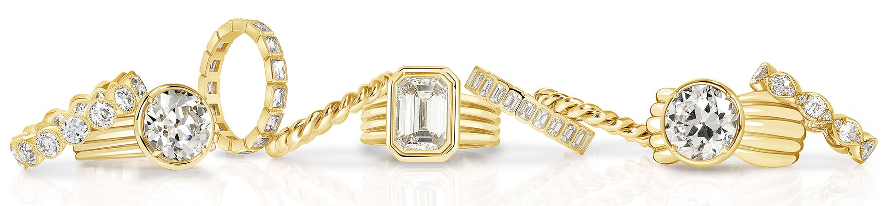 Bold gold diamond rings from Single Stone's Eleni collection along with complimentary gold bands, on a white background