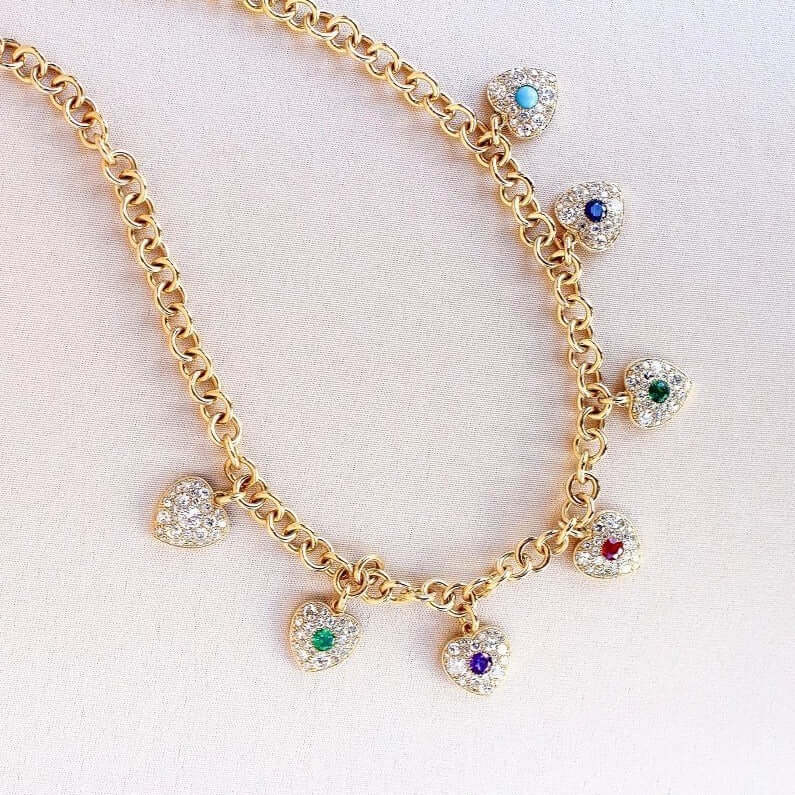 SINGLE STONE DEAREST NECKLACE featuring This colorful Victorian inspired charm necklace showcases a gallery of gemstones holding a hidden term of endearment. Within each heart, various gemstones are arranged in order (diamond, emerald, amethyst, ruby, eme