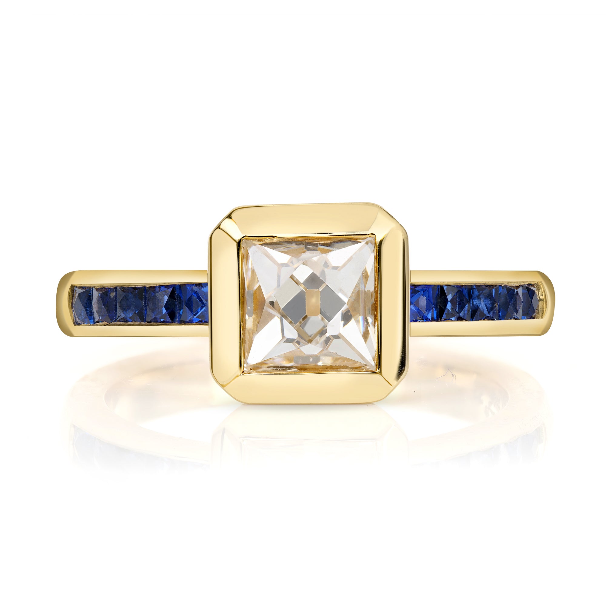 SINGLE STONE KARINA RING featuring 1.15ct K/VS1 GIA certified French cut diamond with 0.39ctw French cut blue sapphire accent stones bezel set in a handcrafted 18K yellow gold mounting.