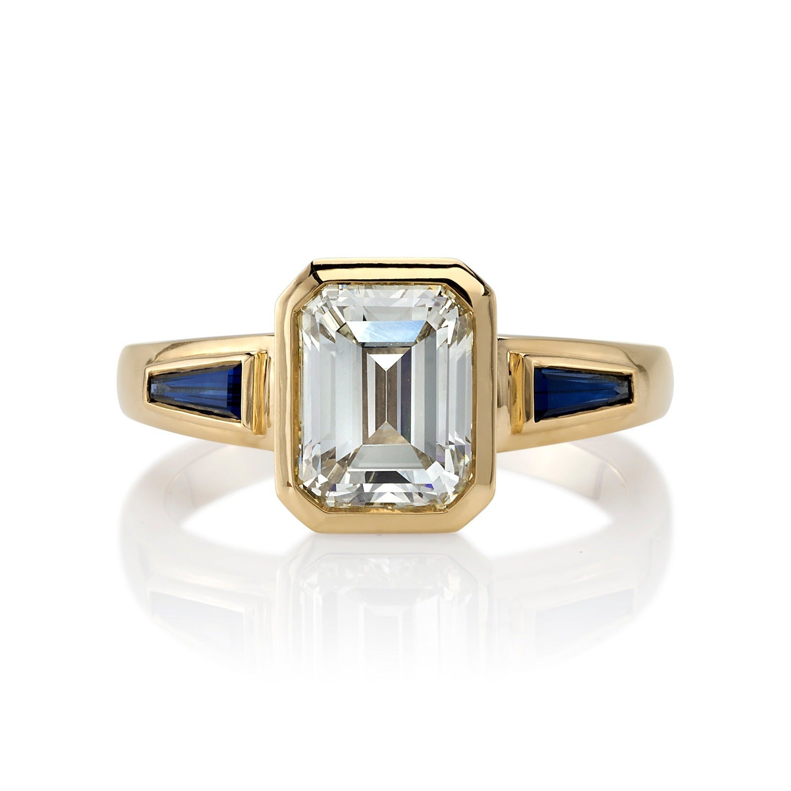 SINGLE STONE LAURIE RING featuring 2.09ct U-V/VS1 GIA certified emerald cut diamond with 0.73ctw baguette cut blue sapphire accents bezel set in a handcrafted 18K yellow gold mounting.