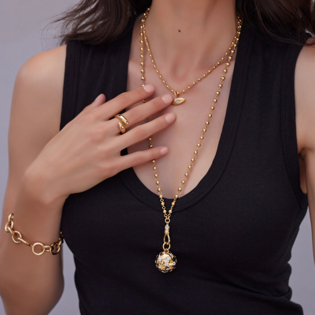 Close up of a woman wearing a ring, necklaces, charms and bracelet from the Single Stone collection