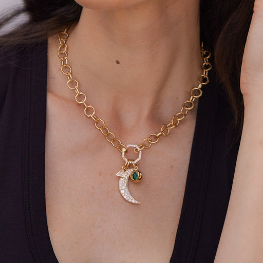 A gold link necklace with a built-in diamond clasp in the center, with three pendants hanging from it, all from the Single Stone collection, around a woman's neck