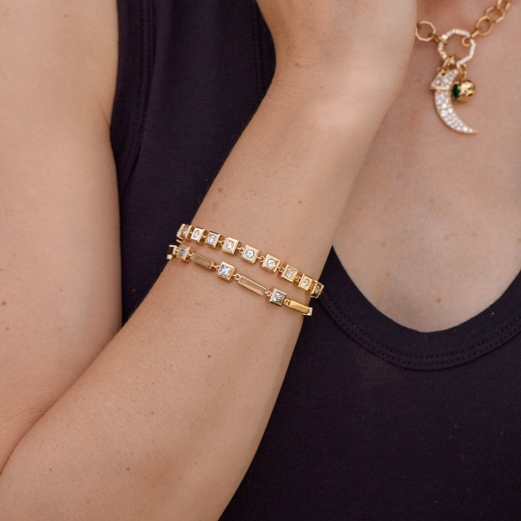 Woman's wrist wearing a stack of Single Stone gold and diamond bracelets