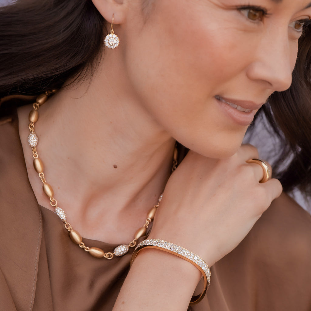 Woman wearing necklace and bangle bracelet from the Single Stone Cobblestone collection and Single Stone earrings, looking off camera