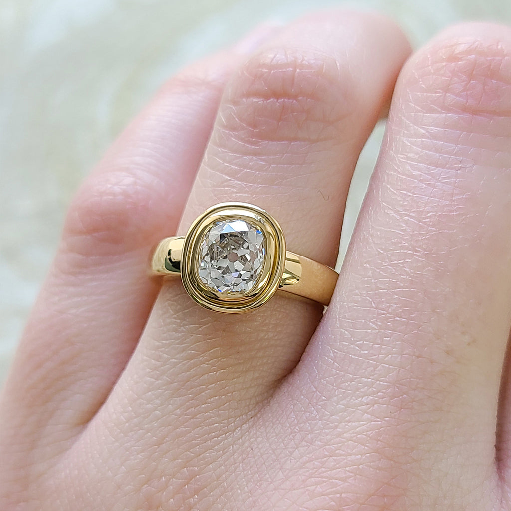 Single Stone's ARIA ring  featuring 1.74ct L/SI1 GIA certified antique cushion cut diamond bezel set in a handcrafted 18K yellow gold mounting.
