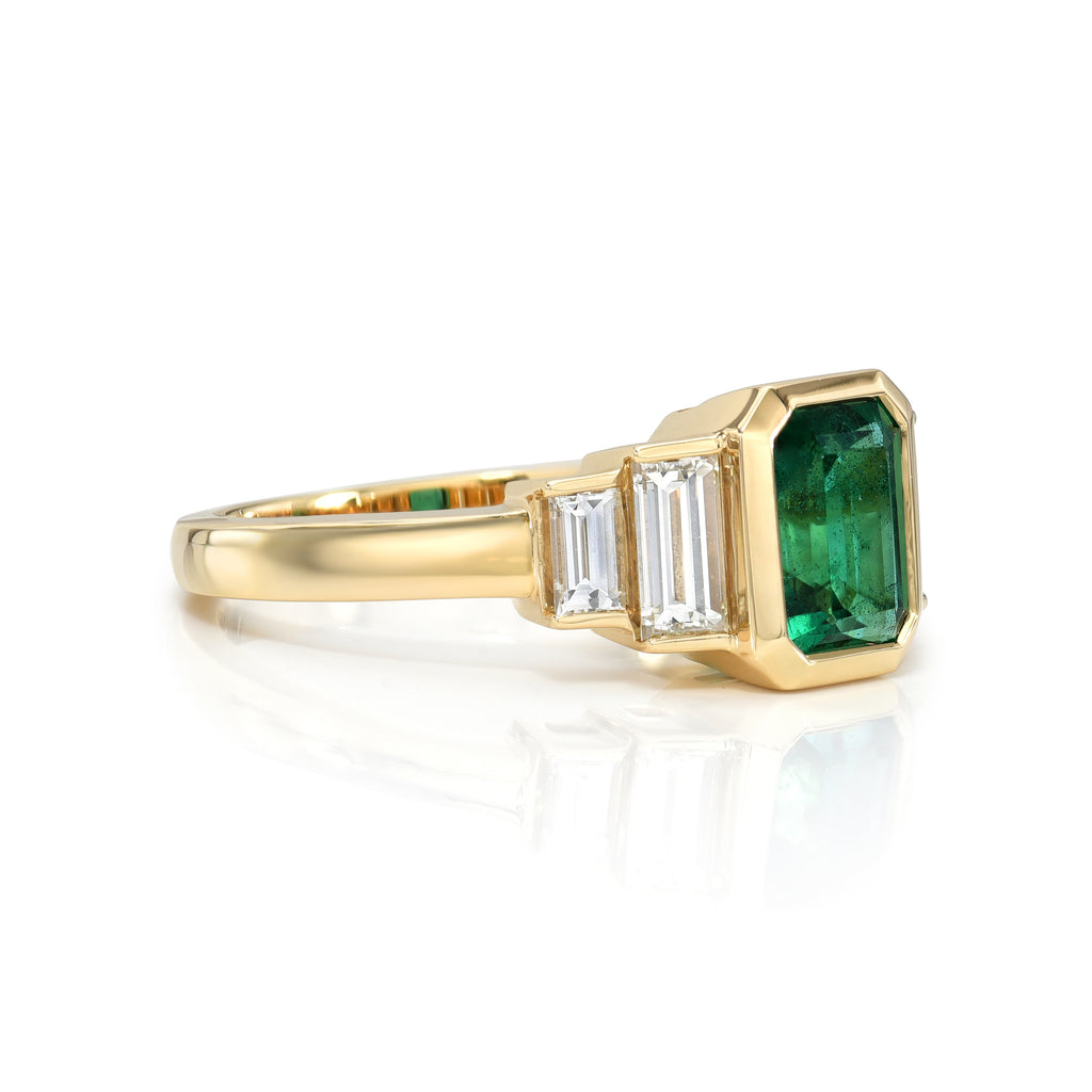 Single Stone's CAROLINE ring  featuring 1.46ct GIA certified Zambian emerald cut green emerald with 0.66ctw baguette cut accent diamonds bezel set in a handcrafted 18K yellow gold mounting.
