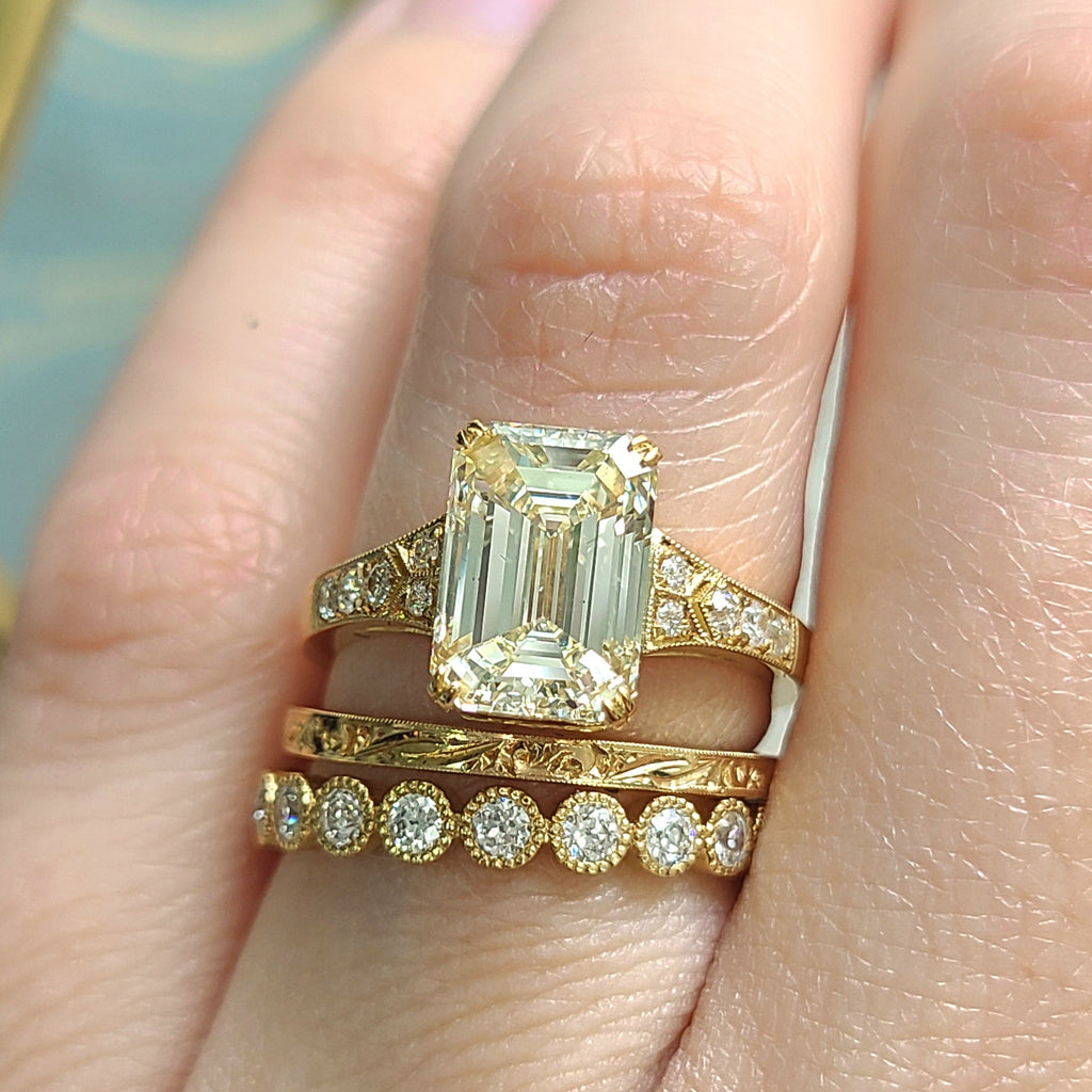 Single Stone's LORRAINE ring  featuring 3.01ct O-P/VS2 GIA certified emerald cut diamond with 0.07ctw old European cut accent diamonds set in a handcrafted 18K yellow gold mounting.
