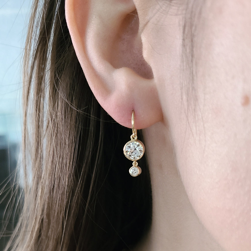 Single Stone's PALOMA DOUBLE DROPS  featuring 1.83ctw I-J/VVS2-VS2 GIA certified old European cut diamonds with 0.18ctw old European cut accent diamonds bezel set in handcrafted 18K yellow gold drop earrings.   
