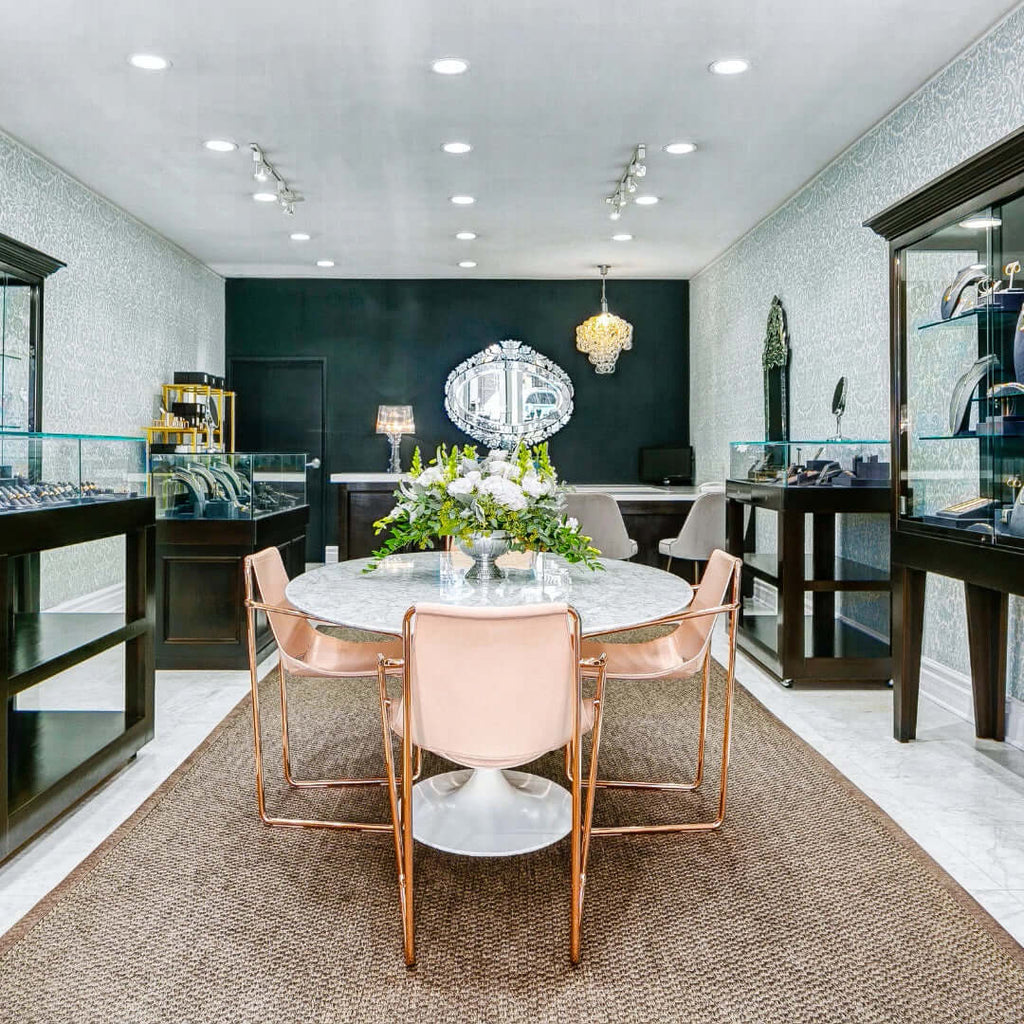 The interior of our flagship store, Single Stone San Marino, showing a marble table with chairs in the center of the space and jewelry cases surrounding the perimeter.