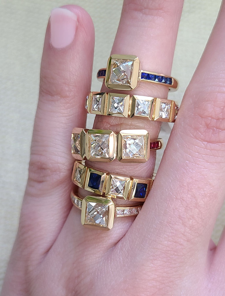French cut diamonds, sapphires and rubies set in Single Stone's 'Karina' rings and bands, stacked on a woman's finger