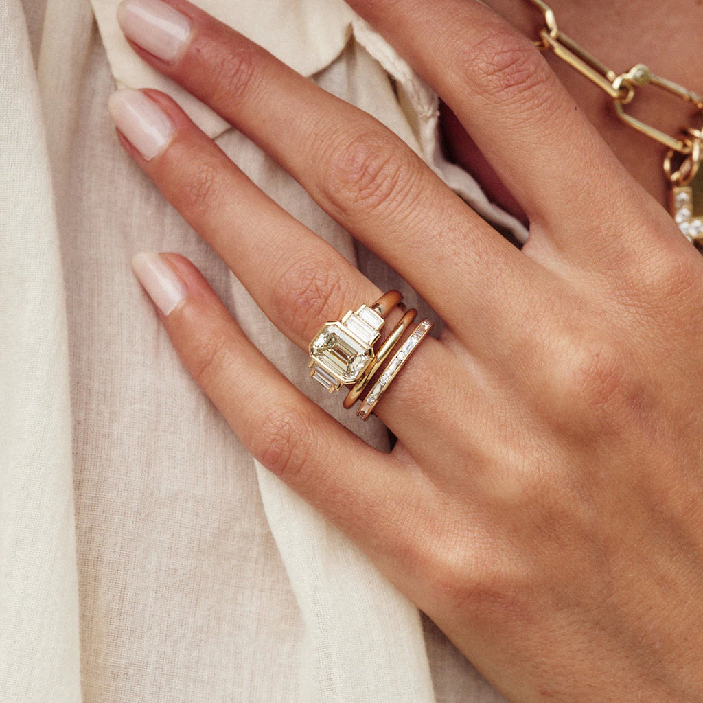 Woman's hand wearing Single Stone's Caroline ring featuring emerald cut diamond center
