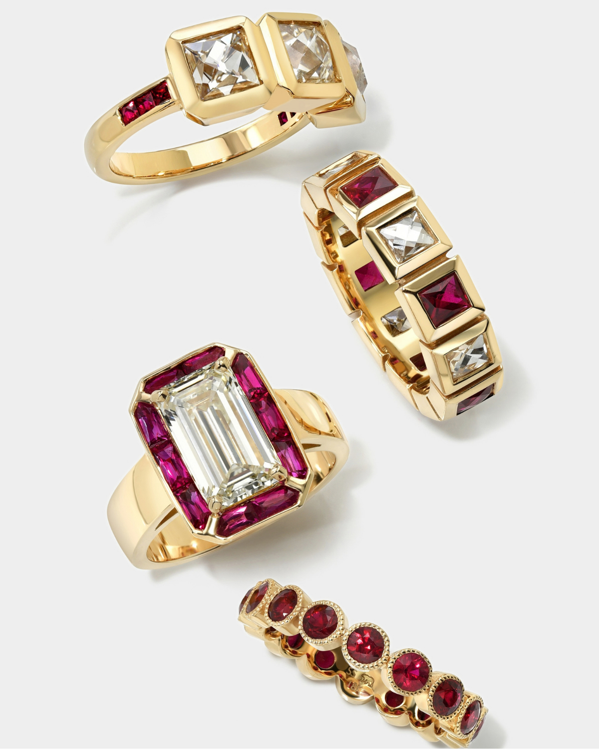 Four gold rings with red and clear gemstones, arranged on a light gray background.