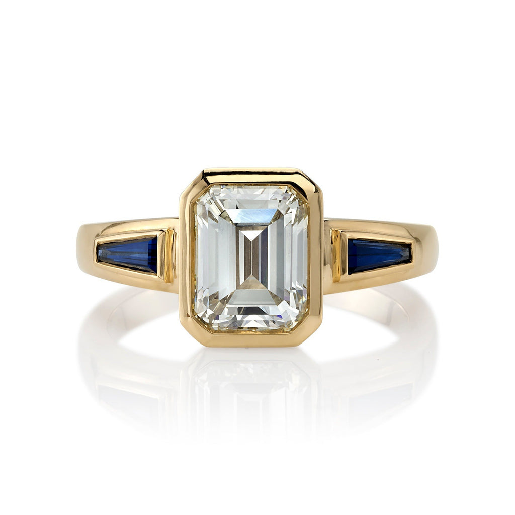 Single Stone's LAURIE ring  featuring 2.09ct U-V/VS1 GIA certified emerald cut diamond with 0.73ctw tapered baguette cut blue sapphires bezel set in a handcrafted 18K yellow gold mounting.
