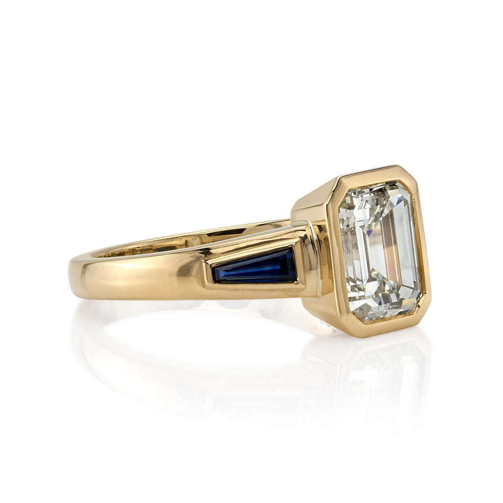 Single Stone's LAURIE ring  featuring 2.09ct U-V/VS1 GIA certified emerald cut diamond with 0.73ctw tapered baguette cut blue sapphires bezel set in a handcrafted 18K yellow gold mounting.
