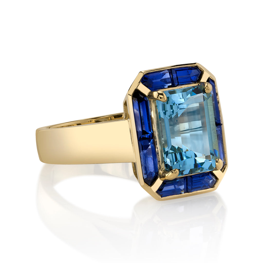 Single Stone's PIPPA ring  featuring 2.63ct emerald cut aqua surrounded by 1.25ctw French cut blue sapphires set in a handcrafted 18K yellow gold mounting.   
